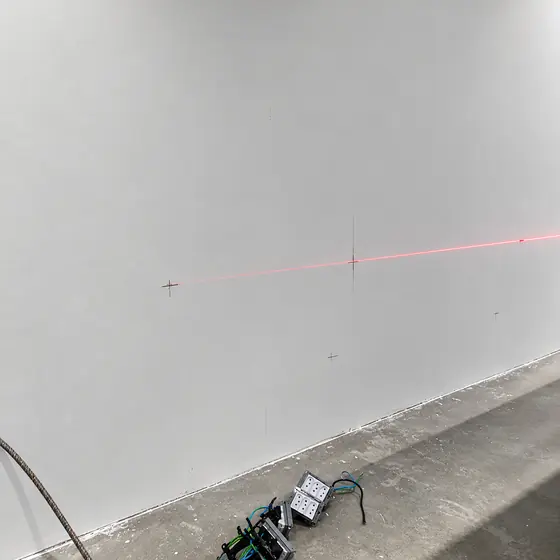 Nível a laser marcando a altura dos pontos elétricos na parede